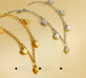 Detailed close-up of 18K gold and silver heart pendants with a polished finish