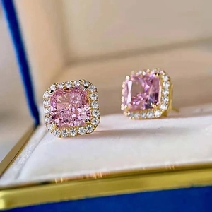 Close-up of pink square-cut gemstone earrings with sparkling diamond halo in gold settings