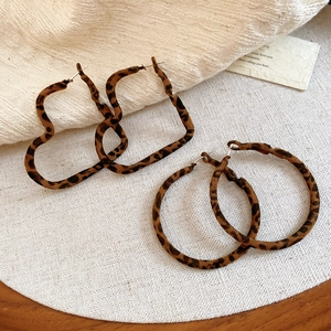 Détail de créoles léopard en forme de cœur et rondes sur un fond esthétique vintage
