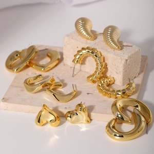 Elegant gold geometric earrings set displayed on a neutral stone textured background