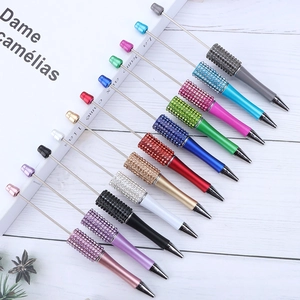 Set of 12 colorful sparkling crystal rhinestone ballpoint pens on white wood surface
