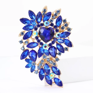 Close-up of golden alloy brooch with blue heart-shaped crystals and small round gems