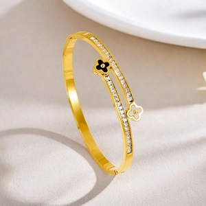 Detailed view of gold plated bangle with black white clover motifs and pavé cubic zirconia