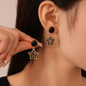Gros plan détaillé de boucles d'oreilles étoiles dorées avec strass noirs portées