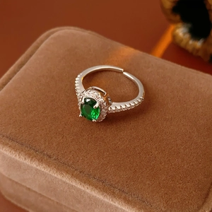 Detail shot of a sparkling green oval zircon ring on a luxury brown velvet jewelry box