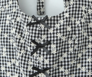 Close-up of black and white gingham dress with white floral embroidery and black bows