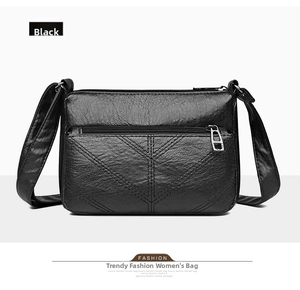 Detail view of black litchi pattern PU leather crossbody bag with silver V-stitch zippers