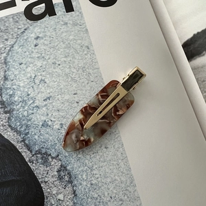 Close-up of brown marble acetic acid hair clip with golden metal clip on magazine