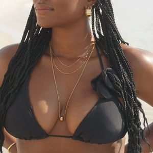 Minimalist double-layered gold stainless steel necklace set worn by a model on the beach