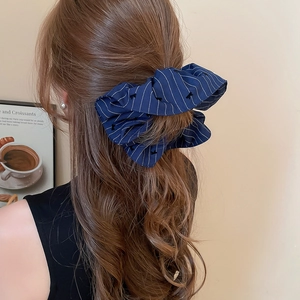 Détail d'un chouchou à rayures et nœuds porté dans une coiffure en queue de cheval