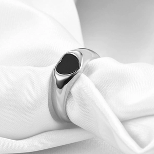 Close-up of a silver stainless steel signet ring with a black heart inlay on white silk
