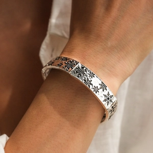 Détail d'un bracelet argenté vintage avec gravure de flocon de neige sur le poignet