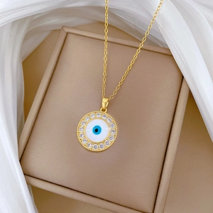 Gold titanium steel necklace with sparkling crystal evil eye pendant on white silk fabric