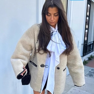 Veste en polaire beige pour femme avec bordure noire et chemisier à nœud blanc
