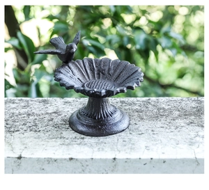 Detail of vintage cast iron sunflower bird feeder with decorative bird and rustic finish