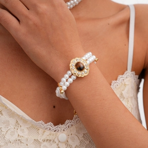Detail of double-layer pearl bracelet with vintage gold flower tiger eye stone charm