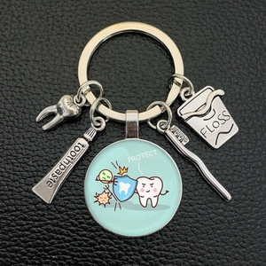 Detail of dental keychain featuring toothpaste, floss and toothbrush on black leather