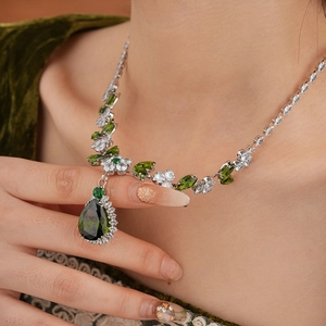 Detail of leaf and flower necklace with green teardrop zircon and white crystal pendant