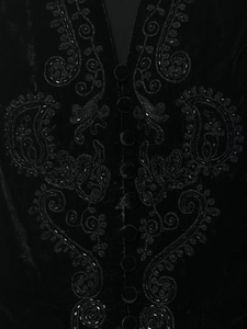 Macro shot of black velvet vest featuring intricate floral embroidery and beadwork details