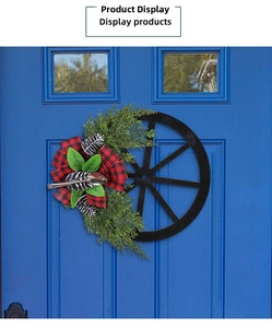 Detail of Christmas wreath with pine cones and black-red plaid bow on a rustic wheel base