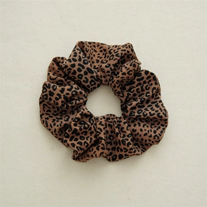 Detail shot of leopard print scrunchie fabric showing soft texture and elastic pleats