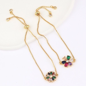 Detail of adjustable gold bracelet with colorful flower-shaped zircon charms on white surface