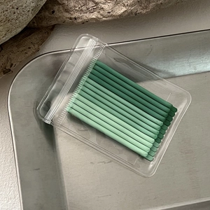 Macro shot of gradient green disposable micro brushes in clear zip lock packaging