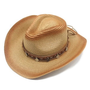 Detail of woven straw cowboy hat with ethnic style band and bronze coin pendants