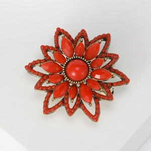 Detail shot of vintage flower brooch with red resin petals and antique gold base