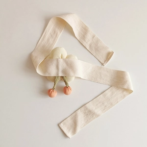 Macro detail of fabric flower curtain tieback with orange berries and cream ribbon