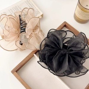 Détail de pinces à cheveux en tulle beige et noir sur un plateau décoratif en bois