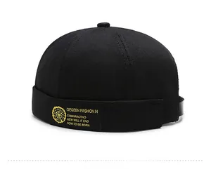 Close-up of black canvas docker hat showing yellow embroidered patch on the side