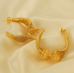 Detail of gold spring earrings with hollow spiral design on champagne satin fabric