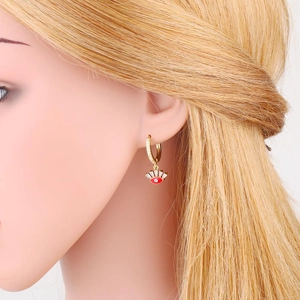 Close-up of golden evil eye drop earrings with red enamel and white zircon on a model