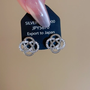 Détail des boucles d'oreilles fleurs en argent serties de zircons sur carte noire