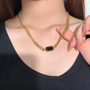 Gold Cuban link necklace with rectangular black gemstone pendant on a female model