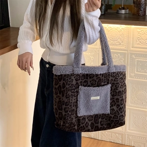 Close-up of leopard print plush tote bag with purple faux fur pocket and brand label