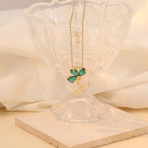 Detail of green clover pendant necklace hanging on glass with cubic zirconia accents