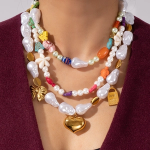 Gros plan d'un collier de perles baroques superposées avec breloques dorées et perles