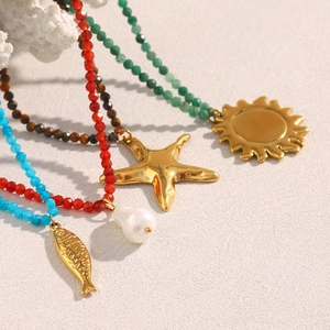 Close-up of beaded necklaces with 18K gold fish, pearl, starfish and sun charms