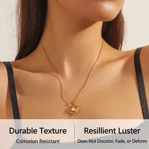 Detail of heart pendant with central pearl on gold snake chain worn by a model