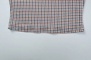 Détail du tissu à carreaux marron et noir avec une couture précise à double aiguille