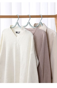 Detail showing space-saving portable travel hangers with white and pink knitted garments