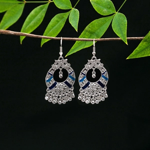 Close-up of ethnic silver hollow earrings with blue enamel and metallic bead tassels