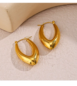 Dettaglio di orecchini ovali cavi placcati oro 18K su una superficie beige morbida