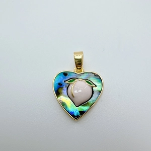 Detailed view of heart-shaped shell pendant with peach motif in 18k gold plating