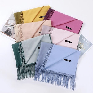 Close-up of stacked colorful cashmere scarves featuring elegant tassels and woven labels