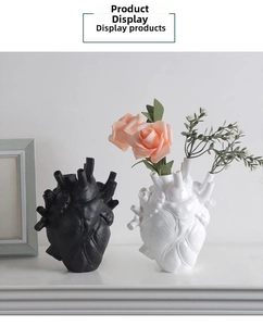 Detail of anatomical heart vases in black and white ceramic with pink flowers