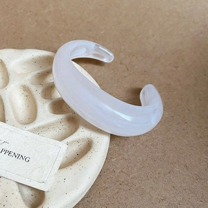 Detail eines durchscheinend weißen Acrylarmbands mit Marmorstruktur auf Keramiktablett