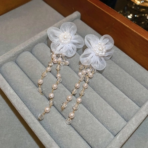 Detailed close-up of lace flower earrings with pearl tassels and crystal beads on velvet